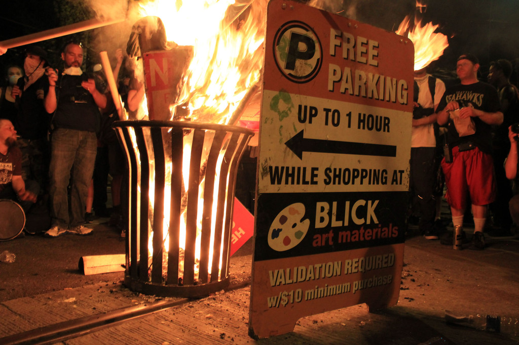 After forcing police from the intersection of Pine and Broadway, revelers set fire to trash and advertisements.