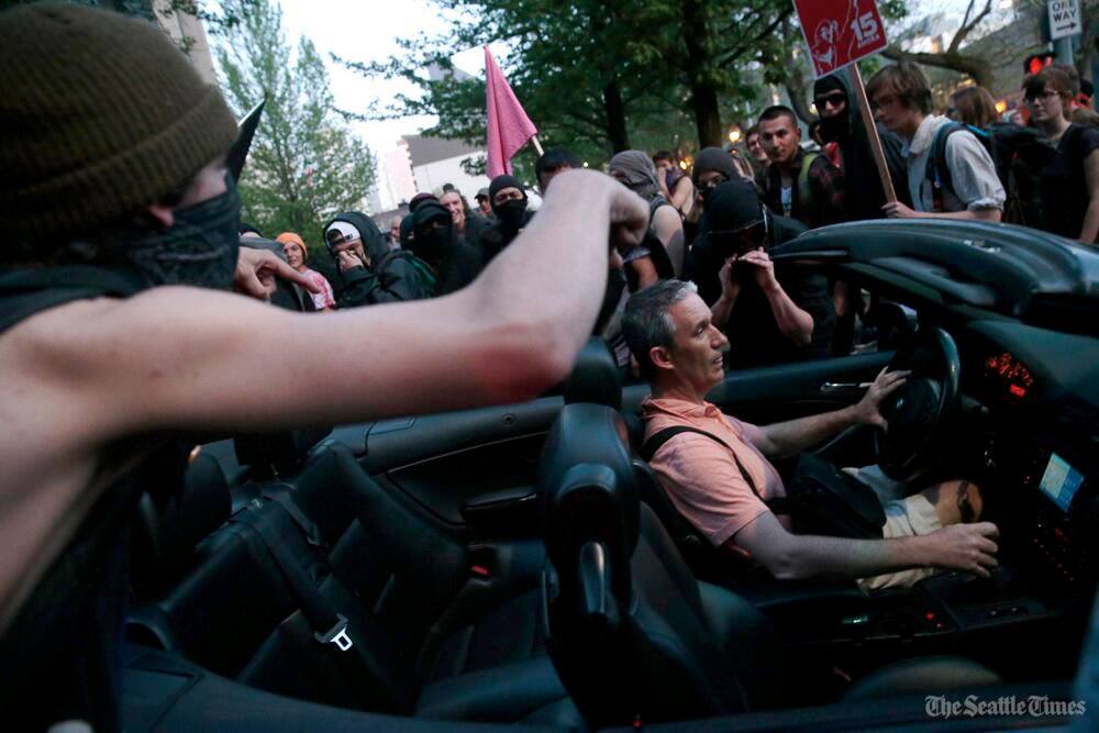 The crowd surrounds a man in a convertible